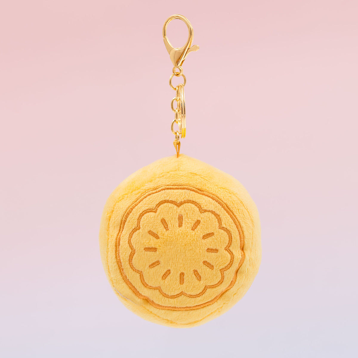 Back view of Chinese mooncake Food Pals bag charm showing a yellow mooncake design with embossed details and a gold clasp