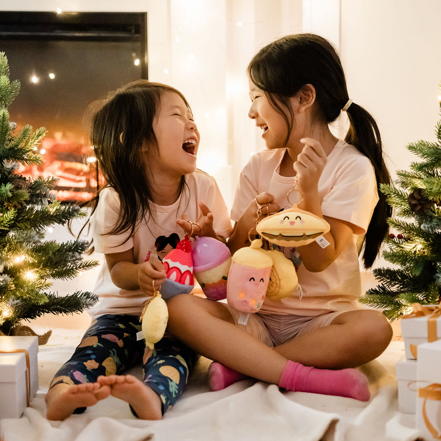 Two children laughing together with Joeydolls Food Pals in front of a fireplace