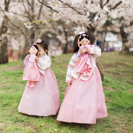 
Two girls in hanbok holding Joeydolls Danbi Korean dolls outdoors

