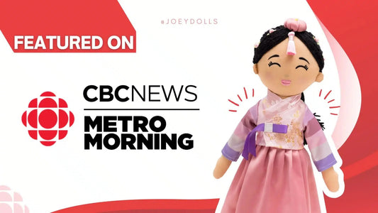 Joeydolls founder Samantha holding a Joeydoll in front of a CBC Radio sign after her Asian Heritage Month interview.