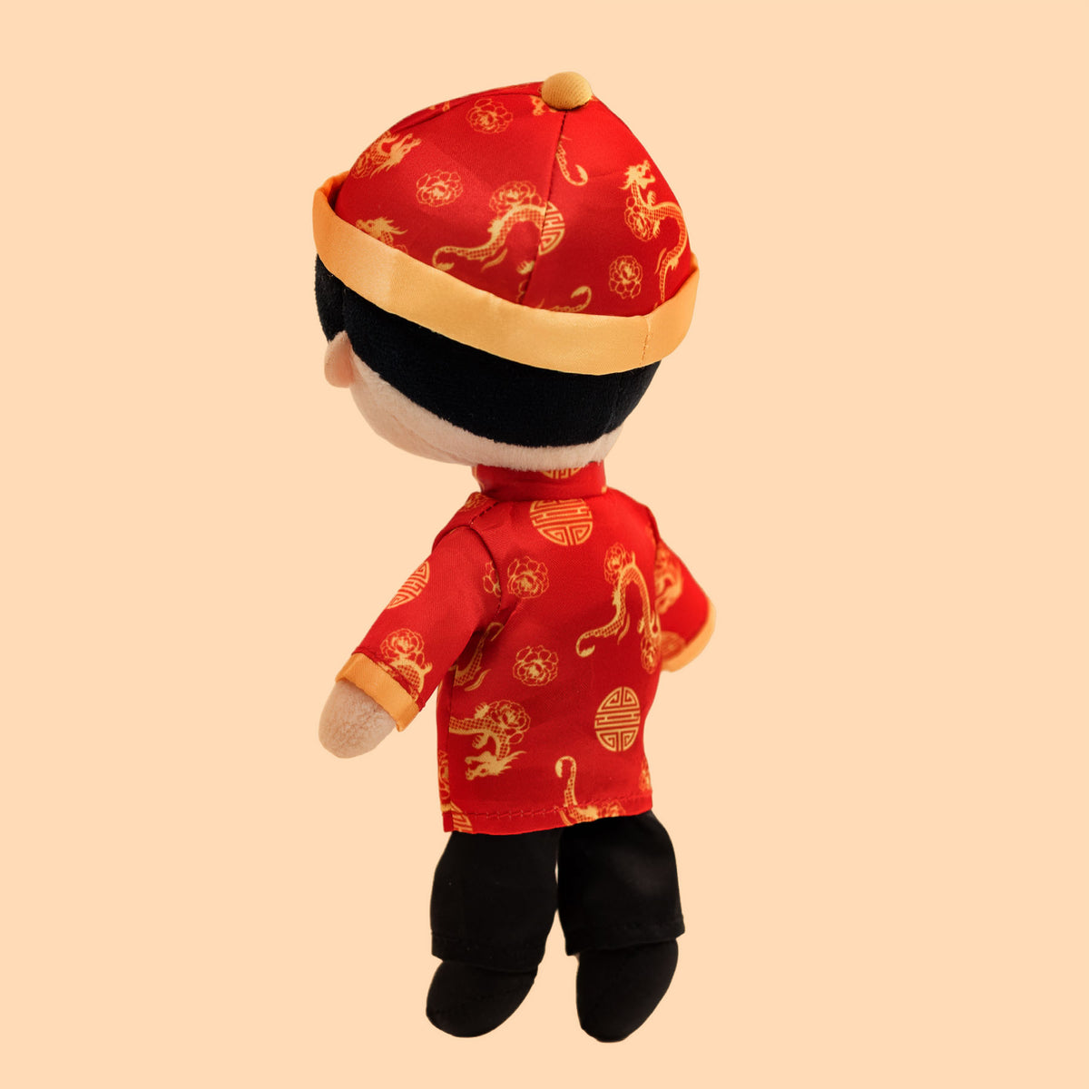 Back view of the Chinese Boy Cultural Mini Doll displaying the detailed red and gold patterned tang jacket, matching hat, black pants, and soft plush design.