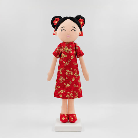 Mei Chinese cultural doll wearing a vibrant red qipao with gold floral patterns, red shoes, and double bun hairstyle adorned with red tassel accessories