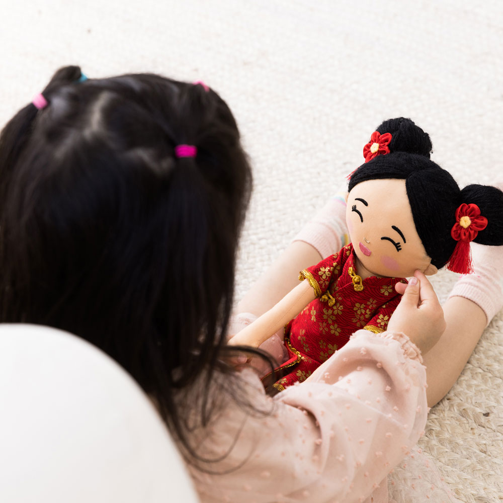 Child playing with a Chinese traditional doll on a light-colored carpet