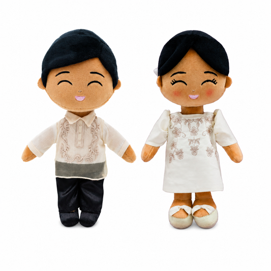 Two smiling plush Filipino dolls standing side by side on a white background. The boy doll wears a cream embroidered barong-style shirt with black pants, while the girl doll wears a white embroidered dress with matching shoes. Both dolls have black hair, rosy cheeks, and embroidered happy expressions.