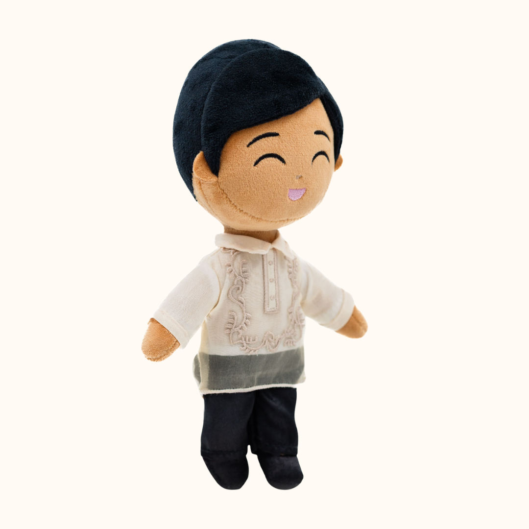 Bayani Filipino boy mini doll wearing a Barong Tagalog-inspired outfit, shown in an angled front view with a smiling embroidered face, black hair, cream traditional shirt, and black pants.