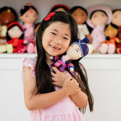 Smiling girl hugging Maiv, the Joeydolls 9-inch Hmong doll