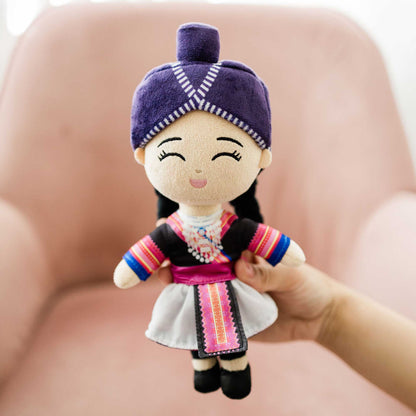 Hand holding Joeydolls Maiv Hmong doll showing the white side of her reversible skirt