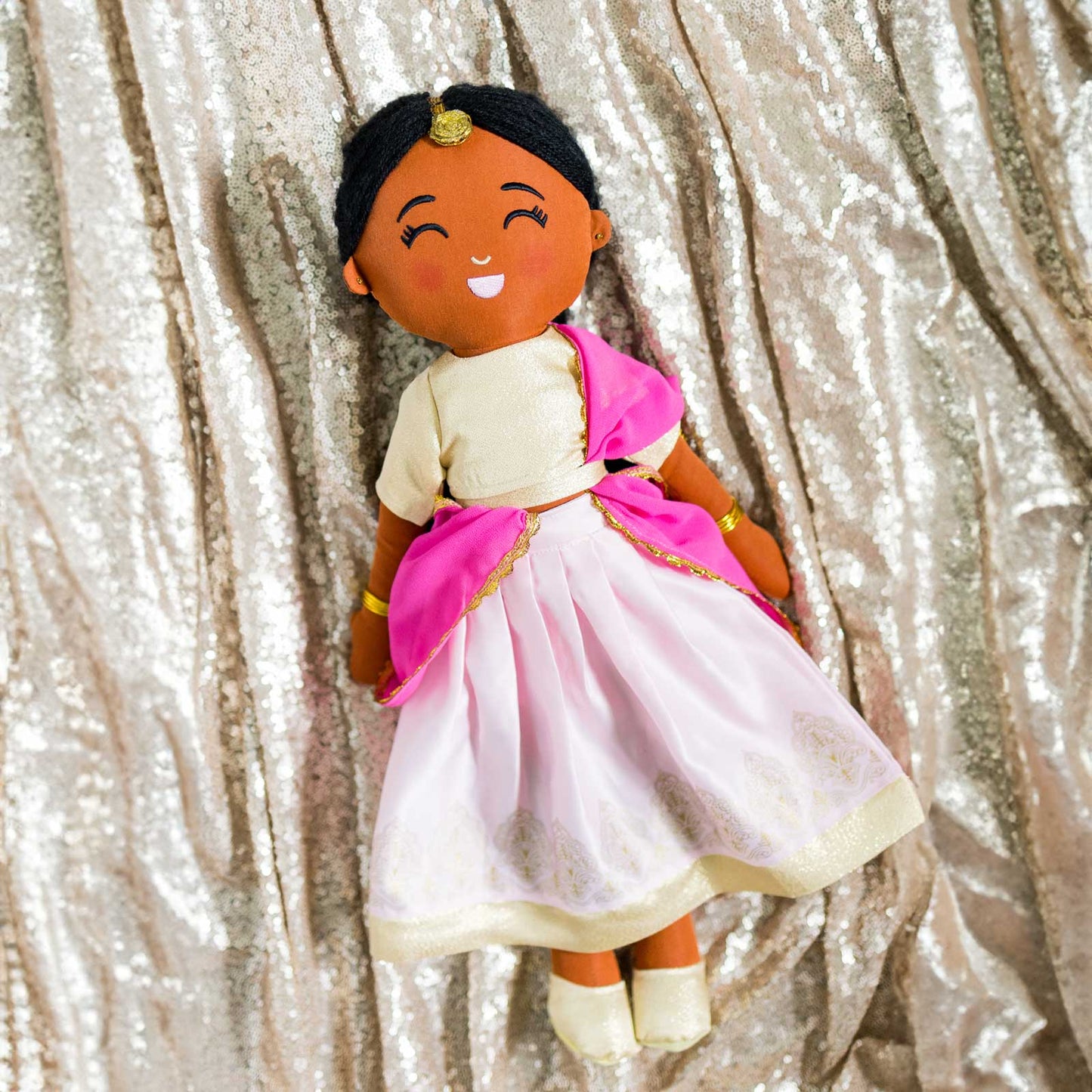 Kamala Indian cultural doll wearing a gold choli top and light pink lehenga with gold embroidery, a pink dupatta, gold jewelry, and a maang tikka in her hair