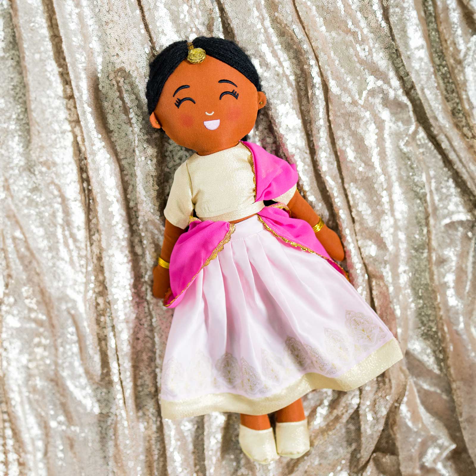 Kamala Indian cultural doll wearing a gold choli top and light pink lehenga with gold embroidery, a pink dupatta, gold jewelry, and a maang tikka in her hair