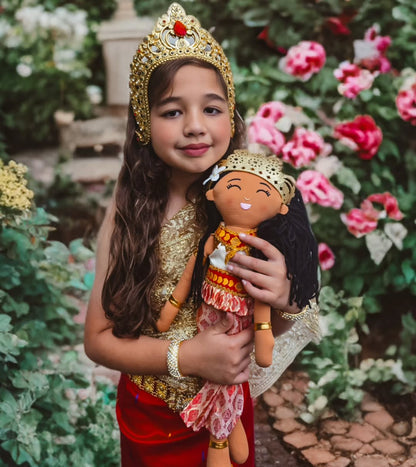 Child holding Soriya Cambodian cultural doll outdoors, wearing traditional attire inspired by Cambodian heritage