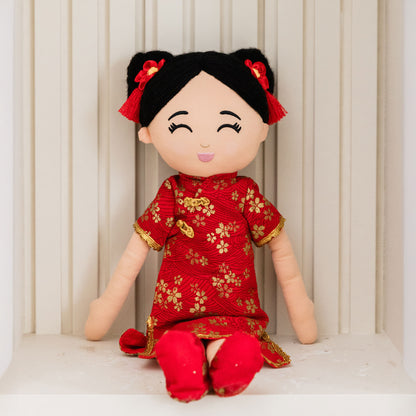 Mei Chinese cultural doll in a front view, sitting with her legs forward.