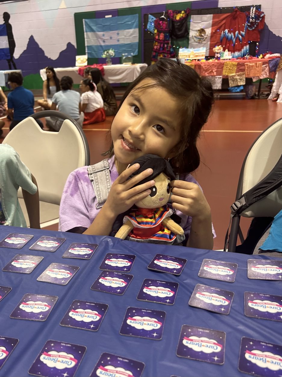 A girl holding her Joeydoll at a Convivir Colorado community celebration