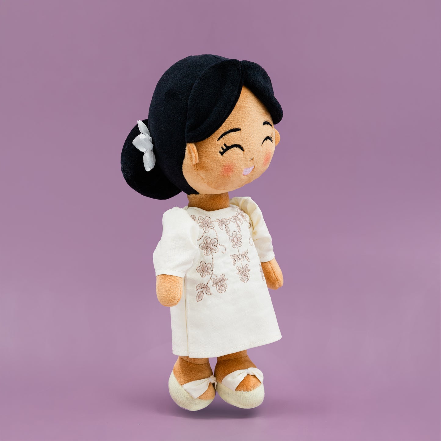 Side angled view of Malaya Filipina cultural mini doll wearing a white Filipiniana dress with butterfly sleeves and white shoes