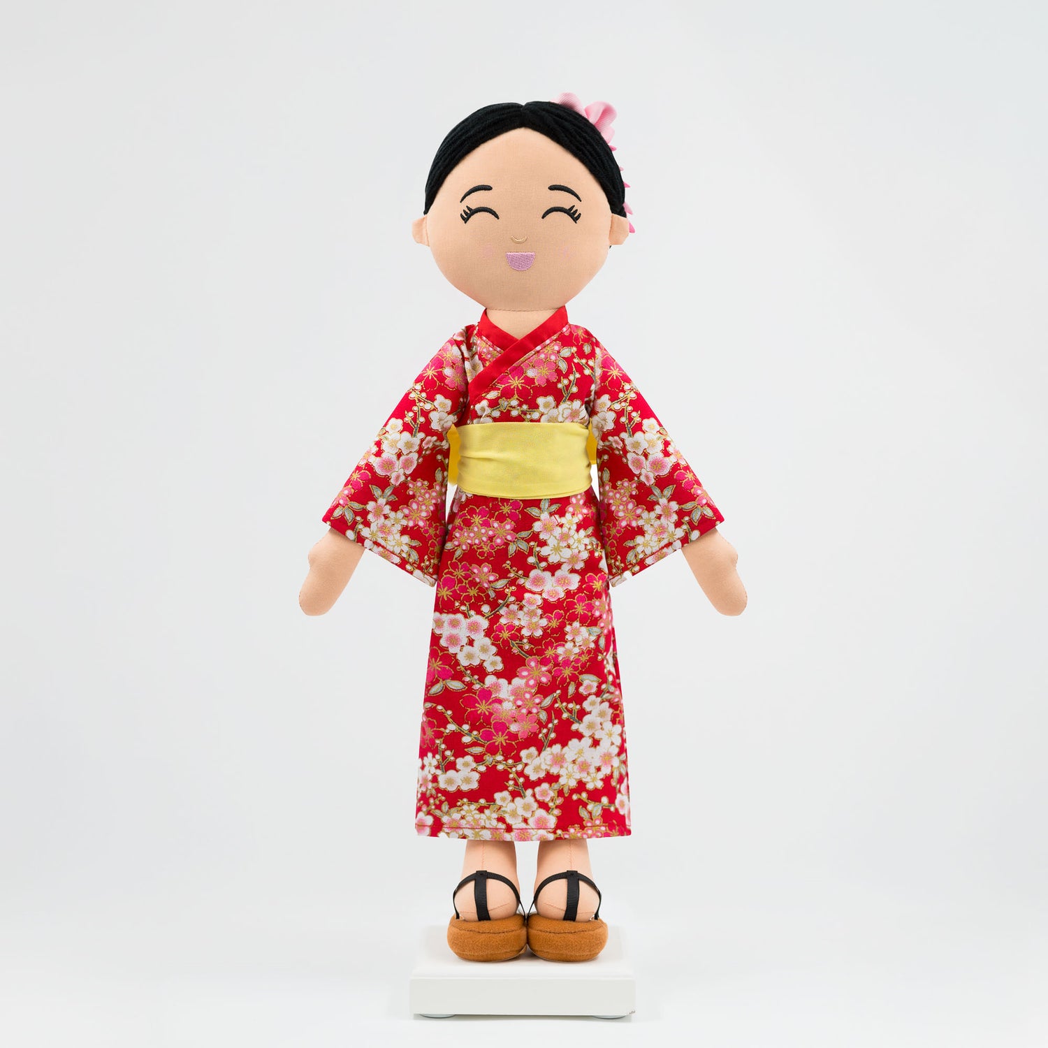 Aiko Japanese cultural doll wearing a red kimono with sakura patterns, a yellow obi, and traditional hairstyle with kanzashi accessories