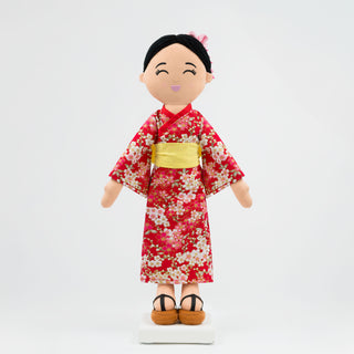 Aiko Japanese cultural doll wearing a red kimono with a yellow obi.