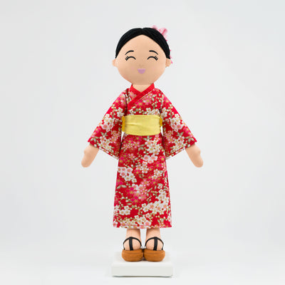 Aiko Japanese cultural doll wearing a red kimono with sakura patterns, a yellow obi, and traditional hairstyle with kanzashi accessories