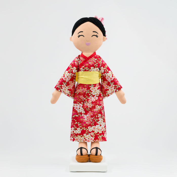 Aiko Japanese cultural doll wearing a red kimono with a yellow obi.