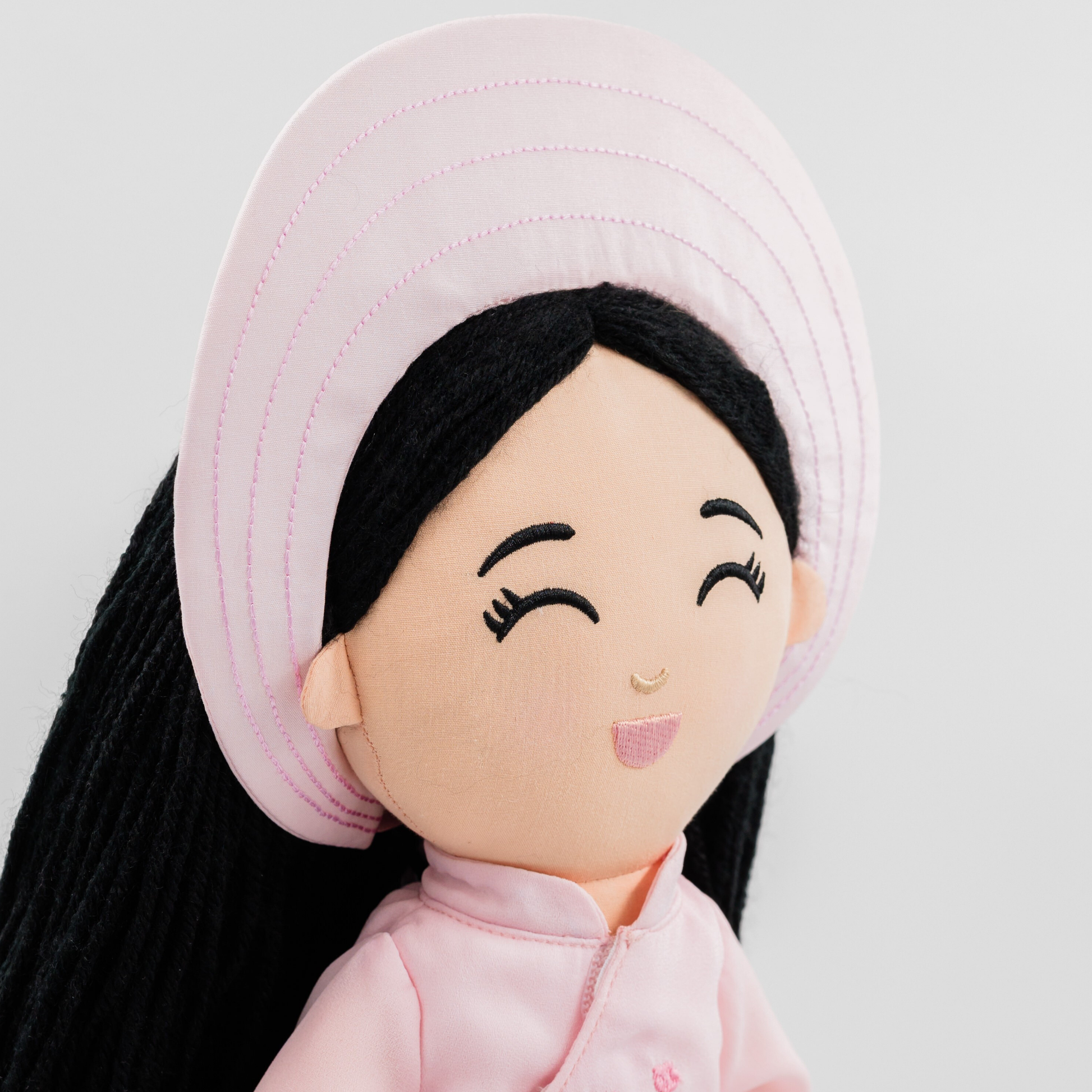 Close-up of Thuong Vietnamese cultural doll wearing a pink khăn đóng headdress and long black hair