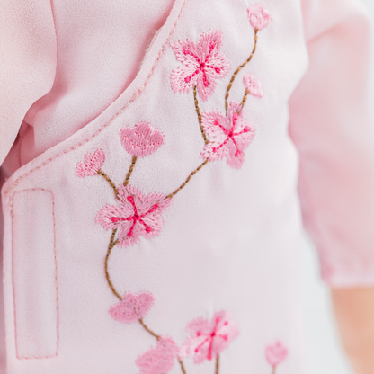 Close-up of cherry blossom embroidery on a pink áo dài worn by Thuong Vietnamese cultural doll