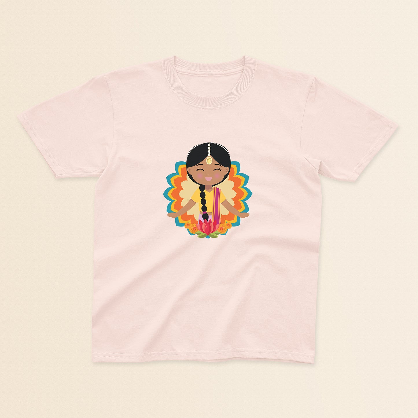 Indian Cultural Celebration baby and kids t-shirt in light pink with a graphic of a smiling girl with long black braided hair with gold maang tikka, wearing a yellow lehenga paired with pink dupatta, set against a mandala-inspired decorative background with a lotus flower at the bottom.