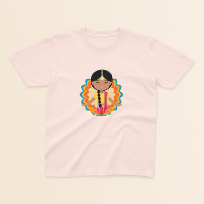 Indian Cultural Celebration baby and kids t-shirt in light pink with a graphic of a smiling girl with long black braided hair with gold maang tikka, wearing a yellow lehenga paired with pink dupatta, set against a mandala-inspired decorative background with a lotus flower at the bottom.