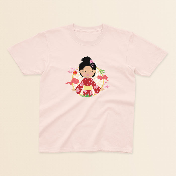 Japanese Cultural Celebration baby and kids t-shirt in light pink with a graphic of a smiling girl with her hair in a high bun with a pink flower, wearing a red sakura-patterned kimono with a yellow obi sash, set against a circular background with cherry blossoms and traditional elements.