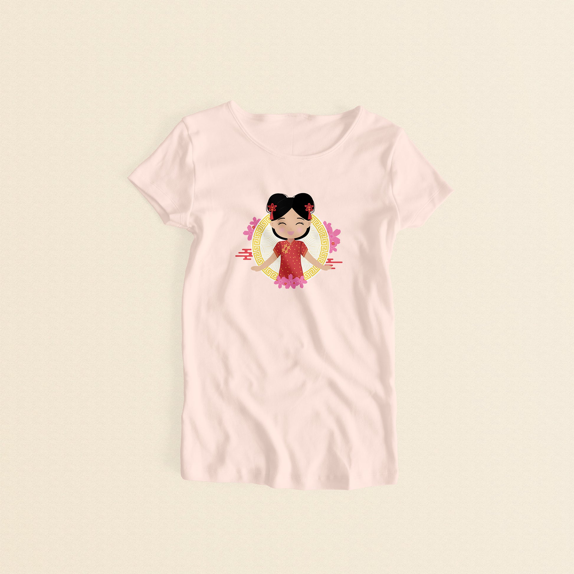 Chinese Cultural Celebration women’s tee in light pink featuring a printed illustration of a smiling girl with her hair in two buns adorned with red accessories, wearing a vibrant red and gold qipao, set against a circular gold pattern with pink floral elements.