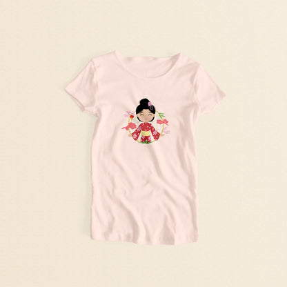 Japanese Cultural Celebration women’s t-shirt in light pink with a graphic of a smiling girl with her hair in a high bun with a pink flower, wearing a red sakura-patterned yukata with a yellow obi sash, set against a circular background with cherry blossoms and traditional elements.