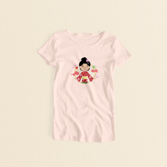 Japanese Cultural Celebration women’s t-shirt in light pink with a graphic of a smiling girl with her hair in a high bun with a pink flower, wearing a red sakura-patterned yukata with a yellow obi sash, set against a circular background with cherry blossoms and traditional elements.