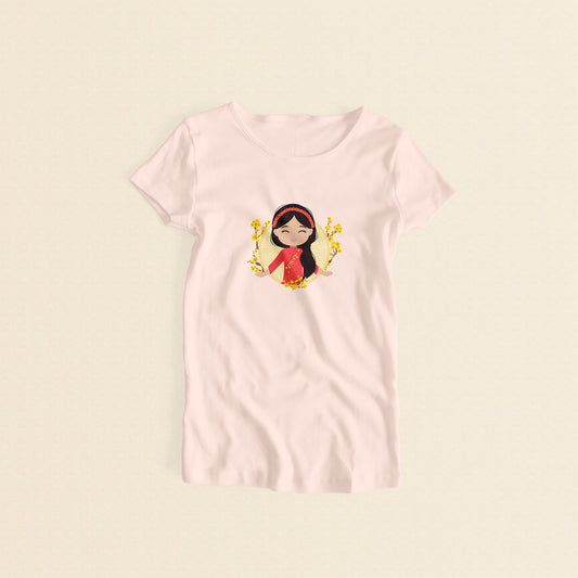 Vietnamese Cultural Celebration women’s tee in light pink featuring a printed illustration of a smiling girl with long black hair, wearing a red áo dài with delicate mai flower details and a traditional khăn đóng headpiece, set against a circular Seigaiha wave pattern background with yellow mai flower branches on both sides.