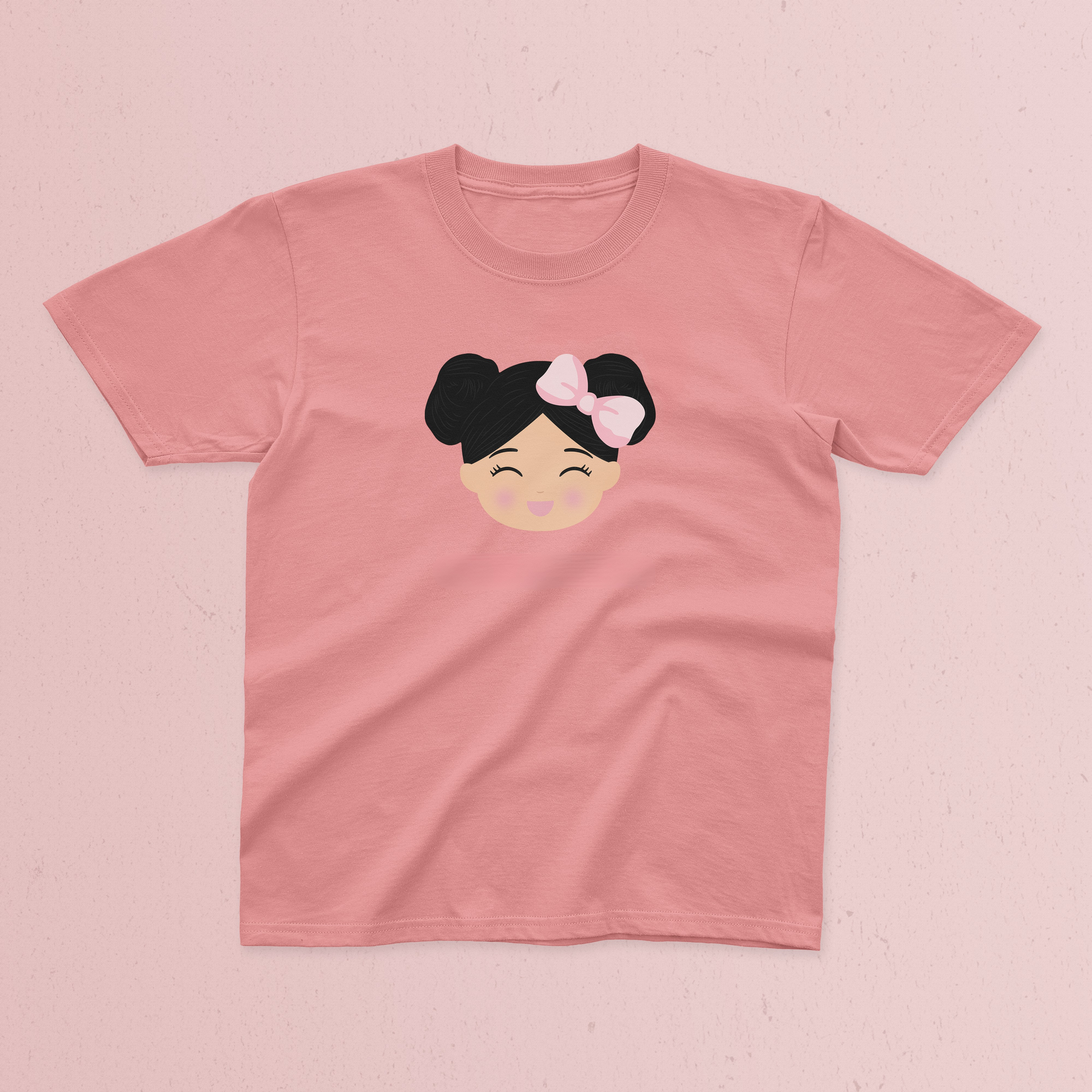 A pink short-sleeve t-shirt with a Joeydolls Icon with black hair in a double bun and a pink bow, displayed flat on a textured pink background.