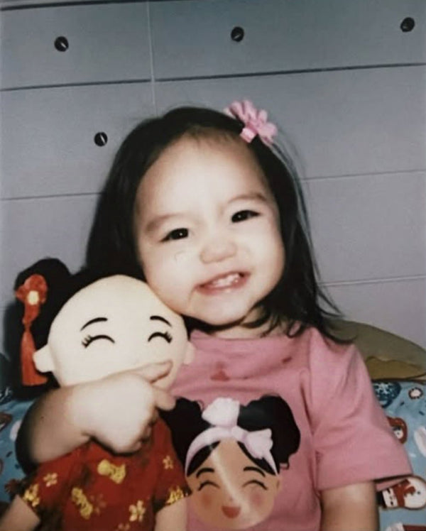 Child hugging a Chinese Mei cultural doll