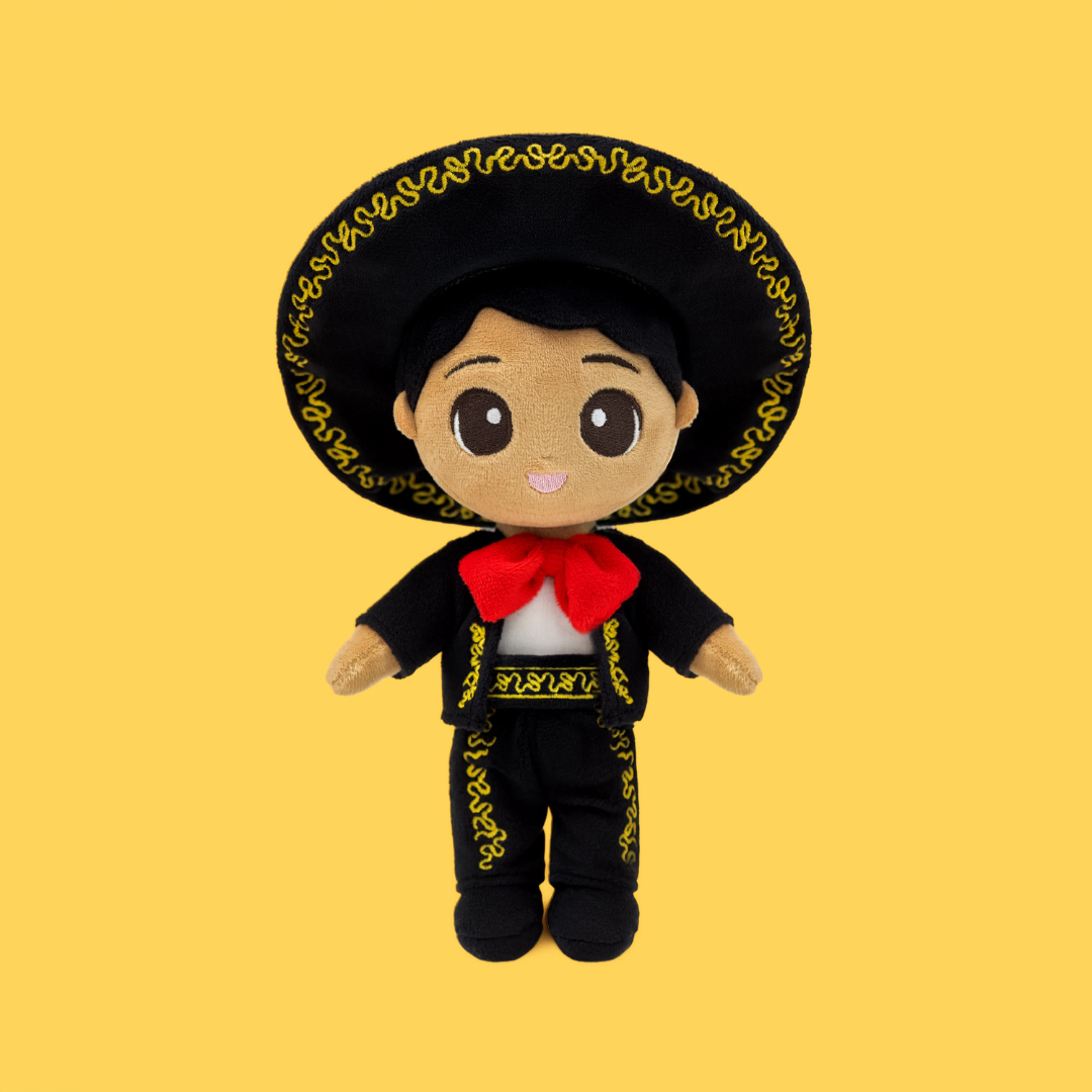 Meet Mateo 🎸 — a name loved across Mexico and beyond. Wearing his traditional Mariachi suit and hat, he celebrates family, music, and the warmth of shared culture and connection. Front-facing plush Mexican boy doll with gold embroidered details, red bow tie, and large sombrero on a yellow background.