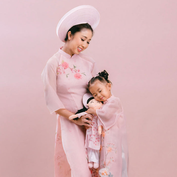 Mother and child wearing matching outfits, holding their Joeydolls cultural doll together