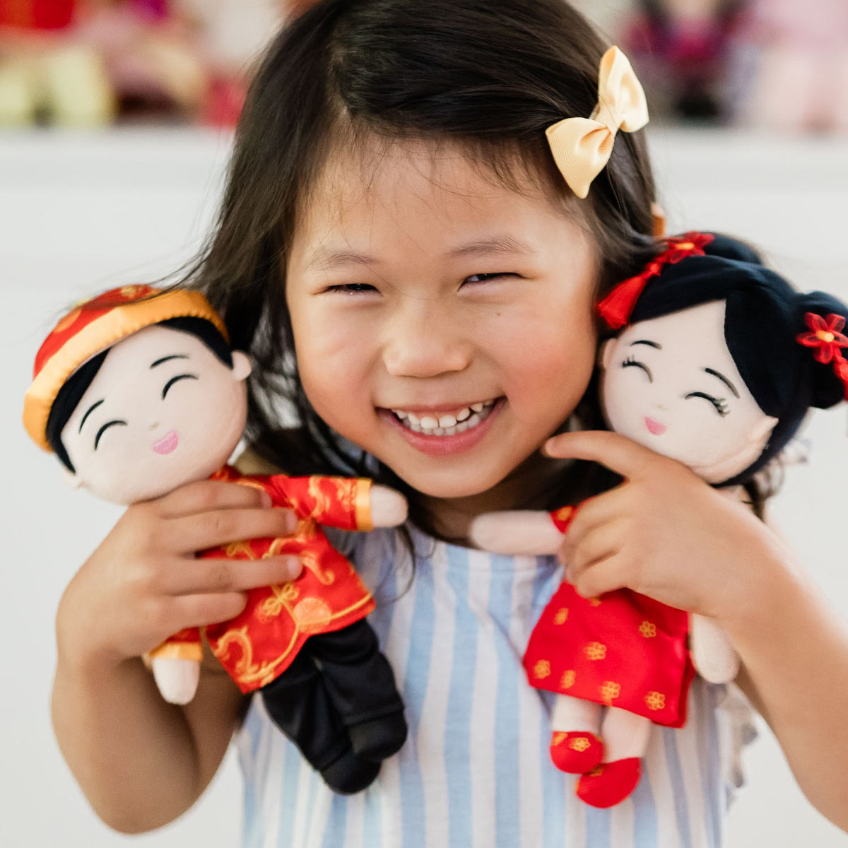 Laughing girl holding Jun, the Joeydolls Chinese boy mini doll in a red tang jacket
