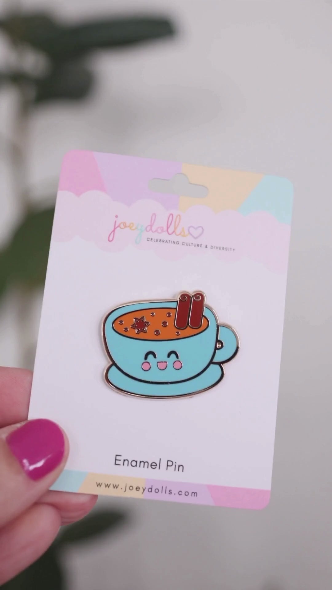Indian masala chai enamel pin on a Joeydolls display card, gently moving to show its blue teacup design, chai with spices, and glossy finish.