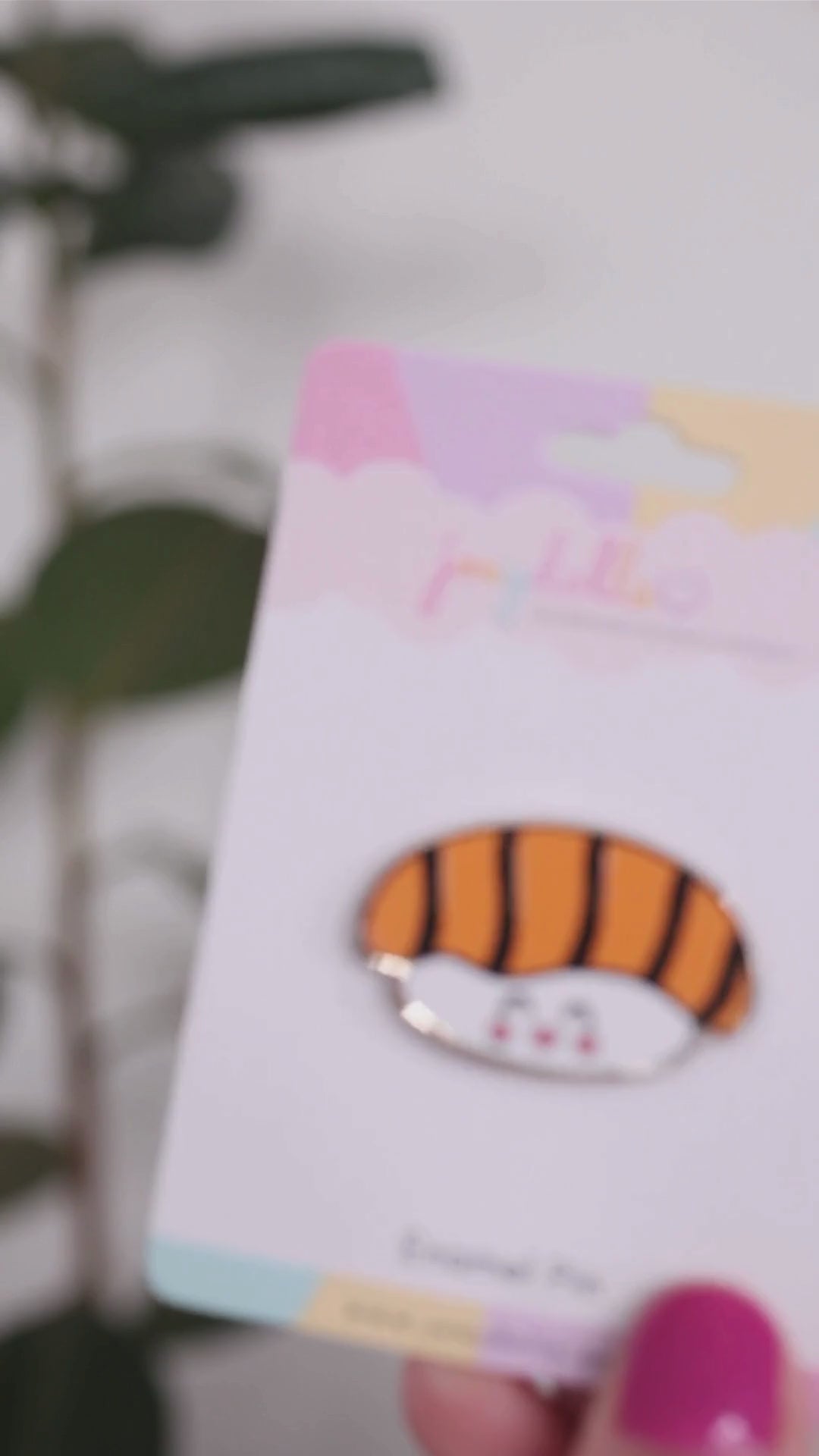 Nigiri Japanese sushi enamel pin on a Joeydolls display card, gently moving to highlight its salmon nigiri design and glossy finish.