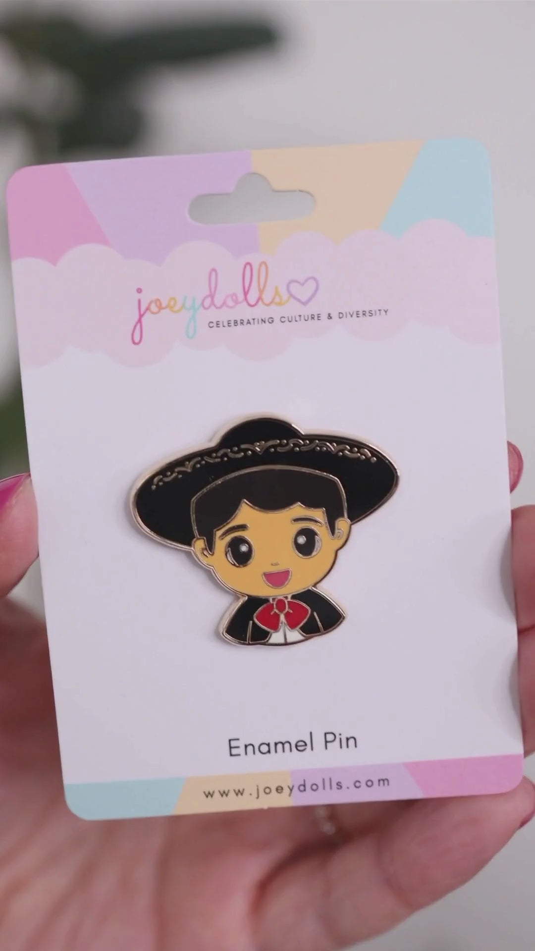 Joeydolls Mexican Mateo gold enamel pin on a Joeydolls display card, gently moving to show its black mariachi suit details and glossy finish.