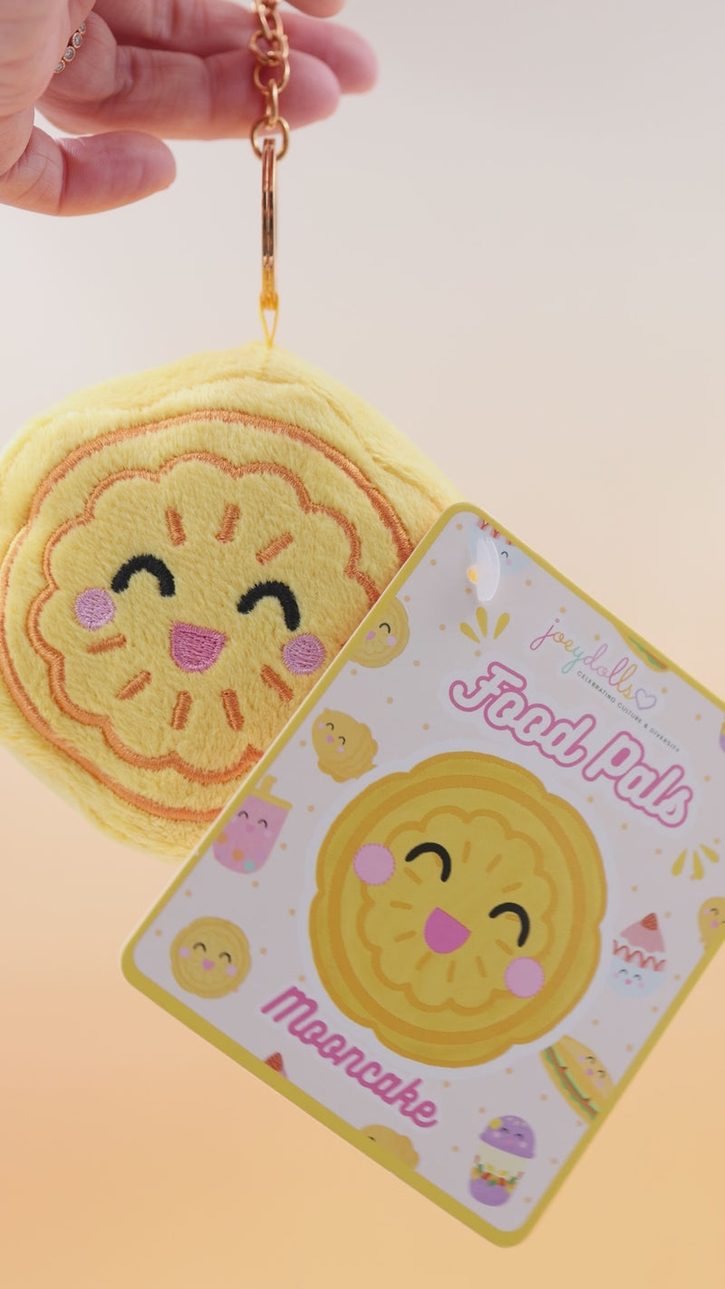 Chinese mooncake Food Pals bag charm being squeezed and rotated, with a gold clasp and attached product tag